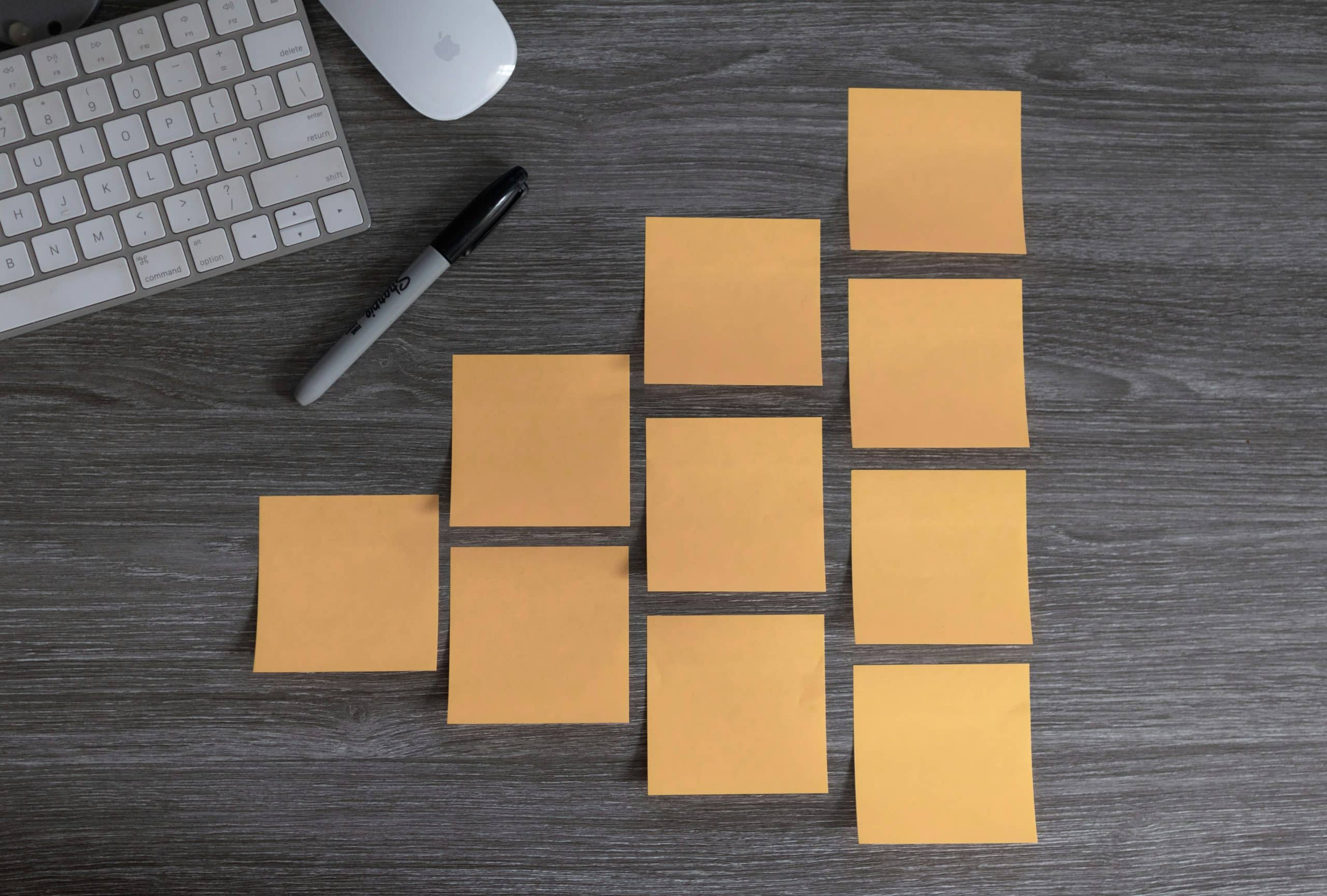 Organizational tools including yellow sticky notes arranged on a desk with a keyboard and marker, symbolizing steps to get organized.